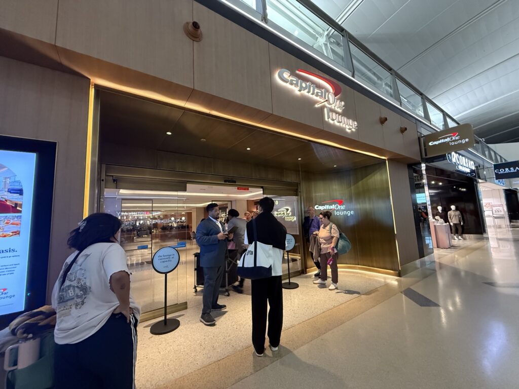 The entrance to the capital one lounge at JFK airport. People are standing outside as it is closed for capacity.