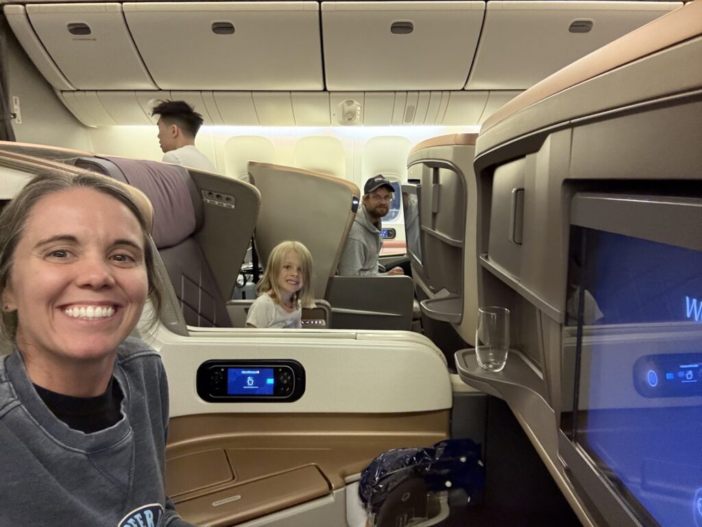 Photo of adult female, 5-year-old child and adult male seated in business class and smiling for a photo.