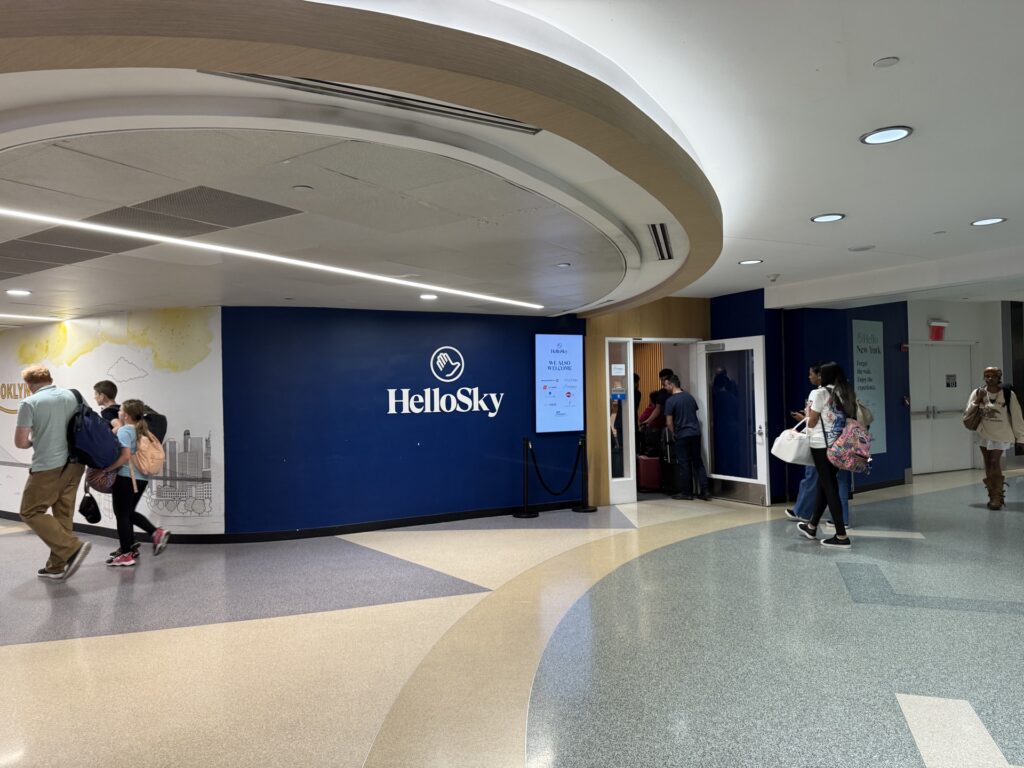 The entrance to the Hello Sky lounge at JFK terminal 4 with people waiting in line to check in.