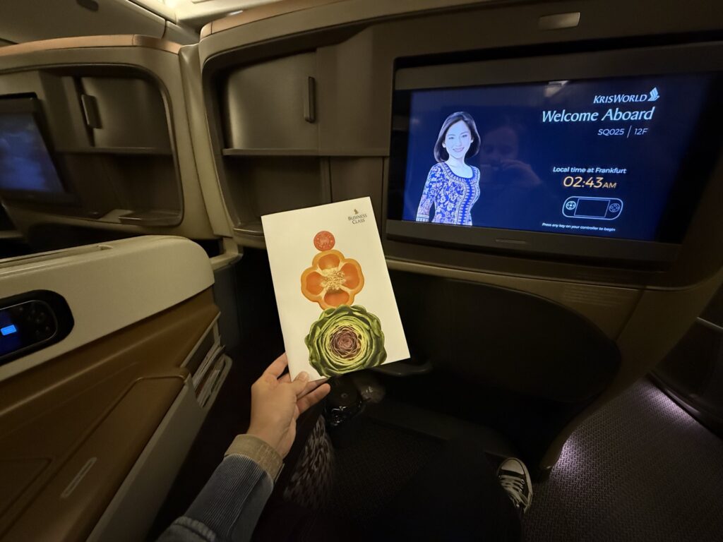 Business Class menu card in front of the center console with a screen that reads welcome aboard.