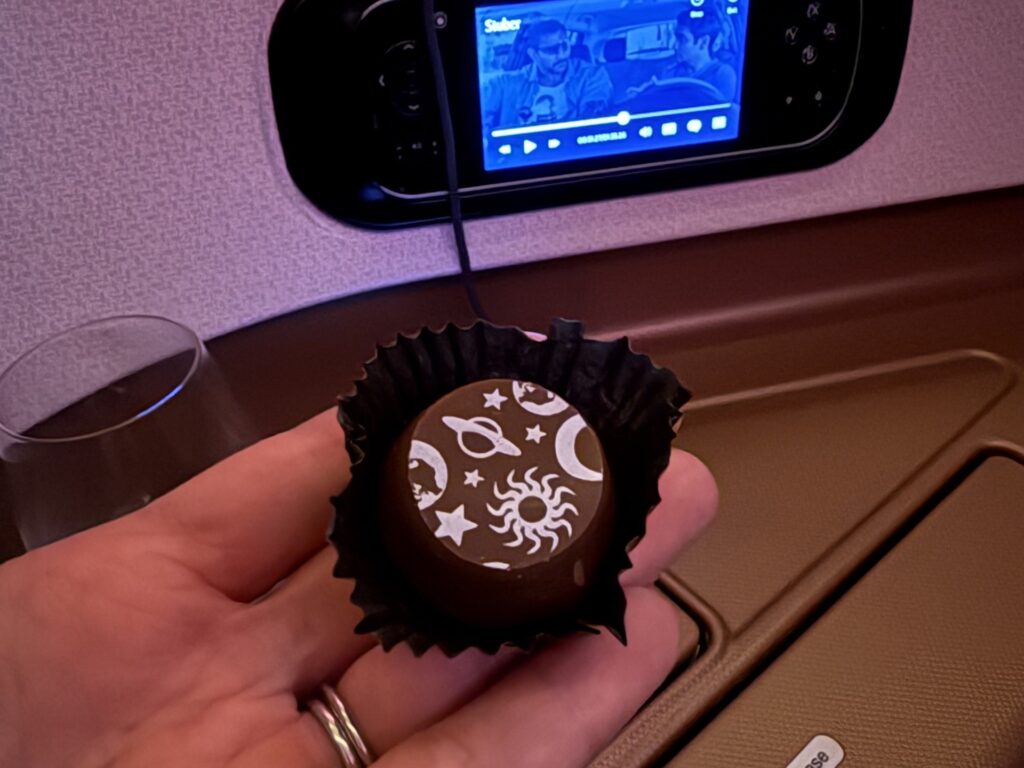 Small chocolate praline truffle withe white space print on top.