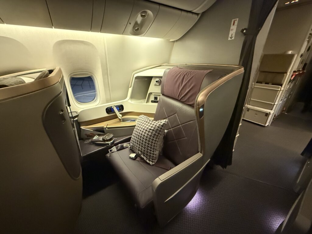 Plush, premium airline seat with pillow on it.